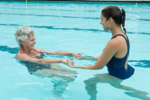 Aquatic occupational therapy, elderly woman training with weights in the pool