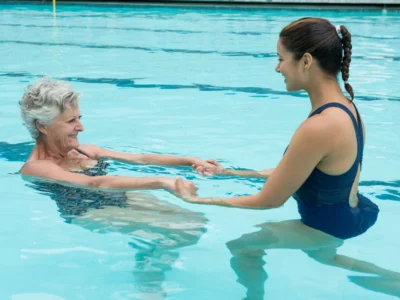 Aquatic occupational therapy, elderly woman training with weights in the pool