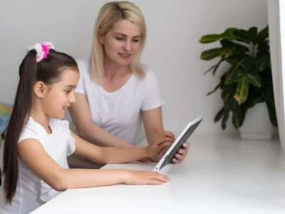 How to work on cognitive stimulation in children with NeuronUP. Therapist next to a girl working with NeuronUP.