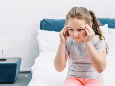 Cognitive stimulation in children with hydrocephalus. Girl touching her head with both hands.