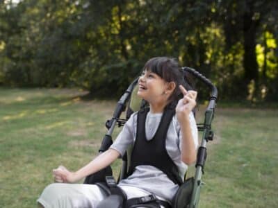 Cerebral palsy: understanding and managing a complex neurodevelopmental condition. Girl with cerebral palsy in a chair outdoors.