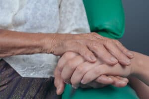 Two hands clasped. Aging of people with Down syndrome.