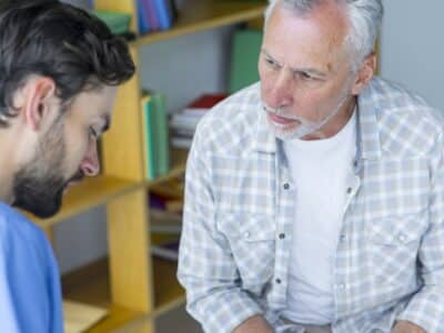 Speech therapy rehabilitation in people with aphasia. A therapist caring for an elderly man.