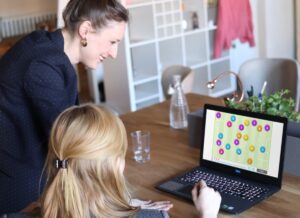 NeuronUP anticipates the risk of cognitive impairment by one year. Mother with her daughter working with NeuronUP digital activities with a computer.