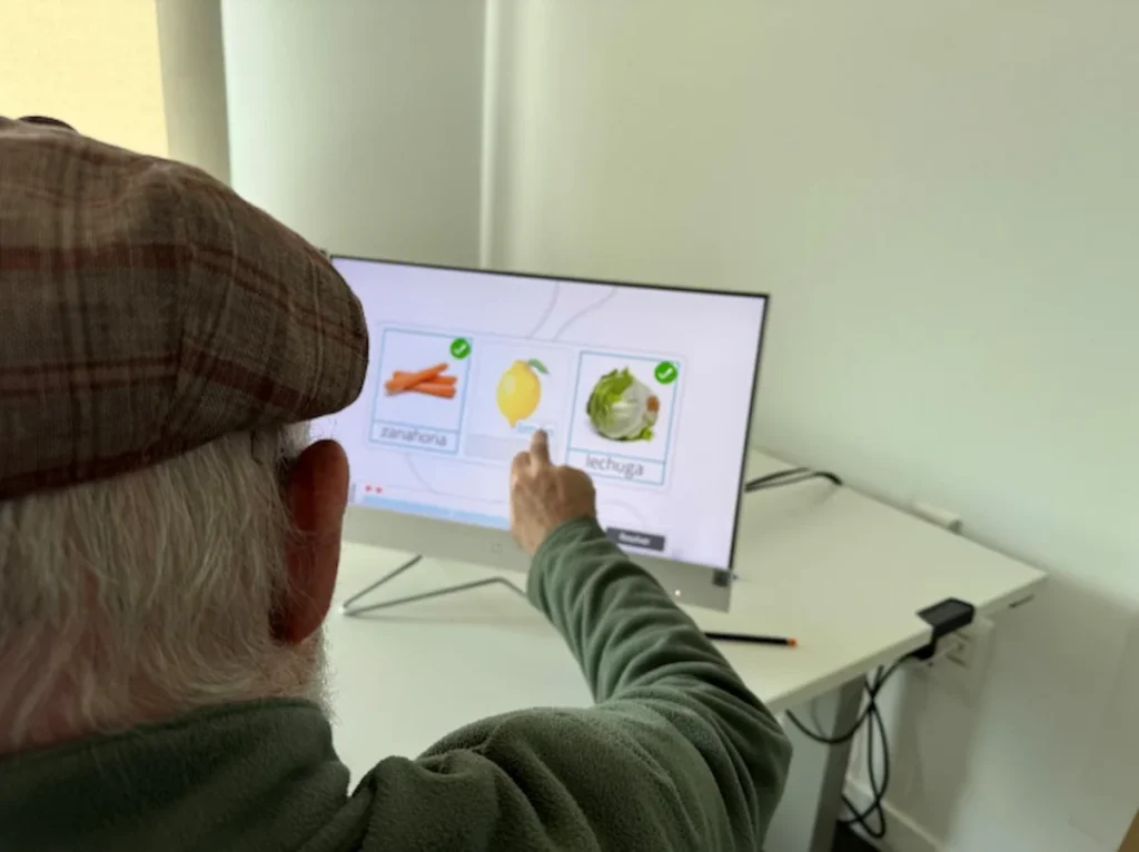 Outpatient clinic patient engaging in computer-based motor aphasia therapy with NeuronUP.