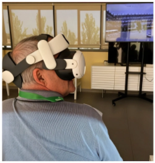Man wearing a virtual reality headset while seated and viewing a screen with images during a pilot study on reminiscence and cognitive stimulation in Alzheimer’s disease.